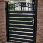 Modern black metal pedestrian gate with horizontal slats and decorative top in London