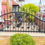 Decorative black wrought iron railings with handcrafted floral leaf details installed on a front garden wall of a London residential property.