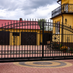 Decorative wrought iron driveway gates with ornate scrollwork installed at a luxury residential property in London.